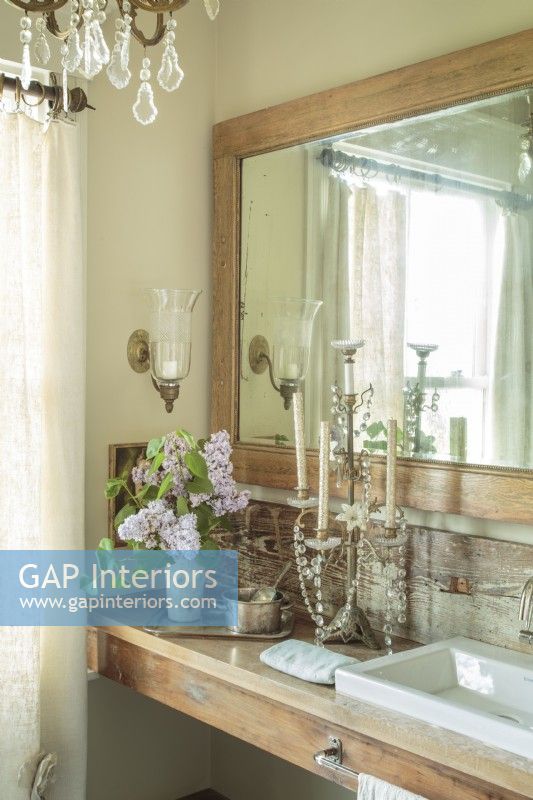 Elegant, feminine bathroom with vintage mirror, wood vanity and chandelier.