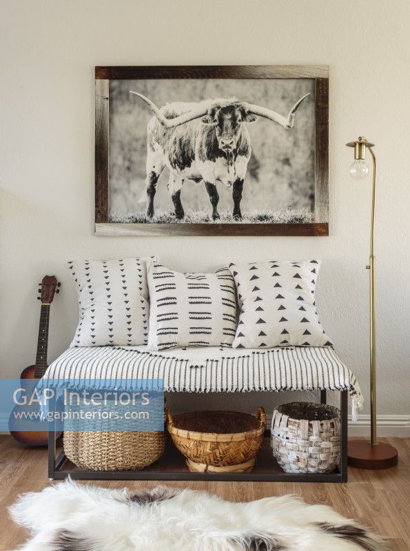 Appreciation for Western culture is on display and includes a favorite print framed using reclaimed wood. Baskets, lamp, and bench textiles contribute to the cozy spot's appeal.