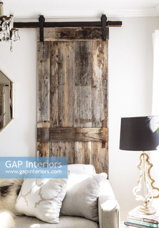A sliding barn door constructed from salvaged wood adds a textural rustic  note to the living room.