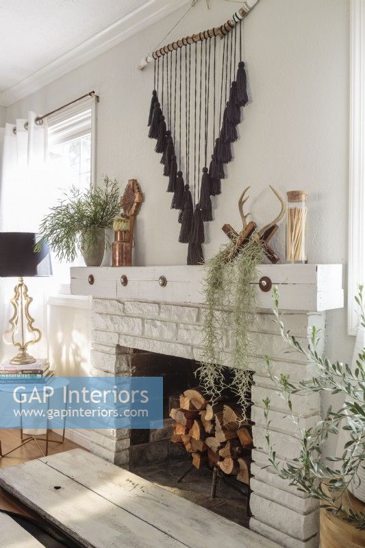  Washed in white, the fireplace is well equipped for chilly nights. .â€ Barely-there window treatments allow intricate pieces, like the tasseled wall hanging to take center stage.