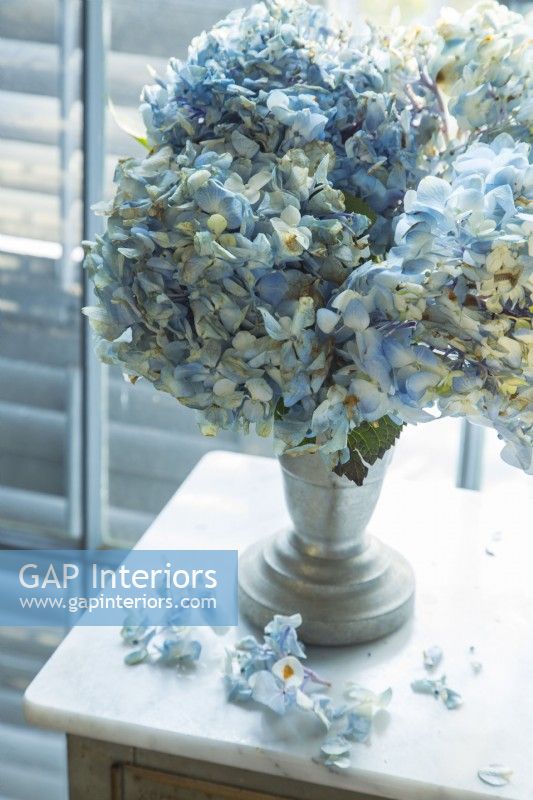 Pale blue hydrangeas nestled in an old container add a romantic note to the bedroom.