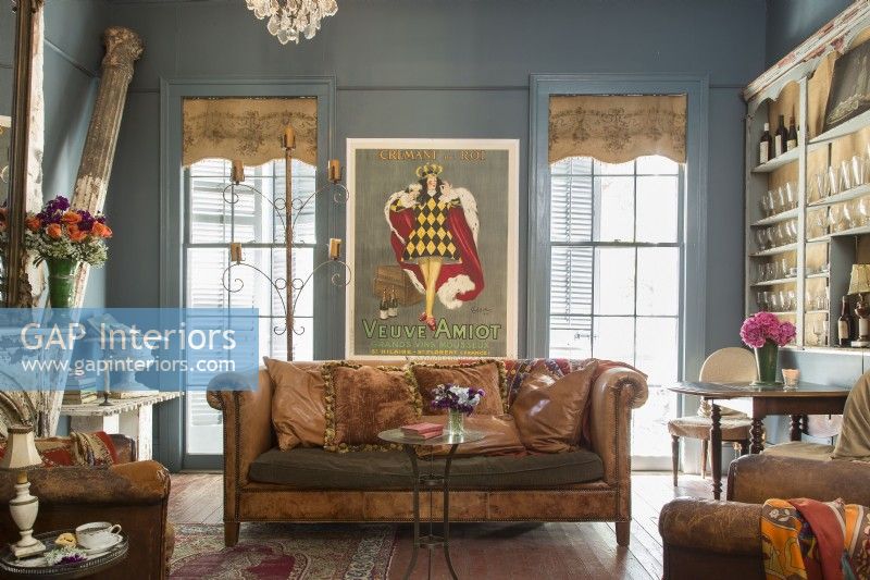 In the living room, an oversize poster by 1920s French-Italian artist Leonetto Cappiello adds drama, along with a salvaged column and a scrolled-arm leather sofa. 