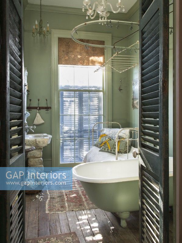 Shutters lead to the bath, where a clawfoot tub and a Turkish marble sink on old stone pavers set an old-world mood.