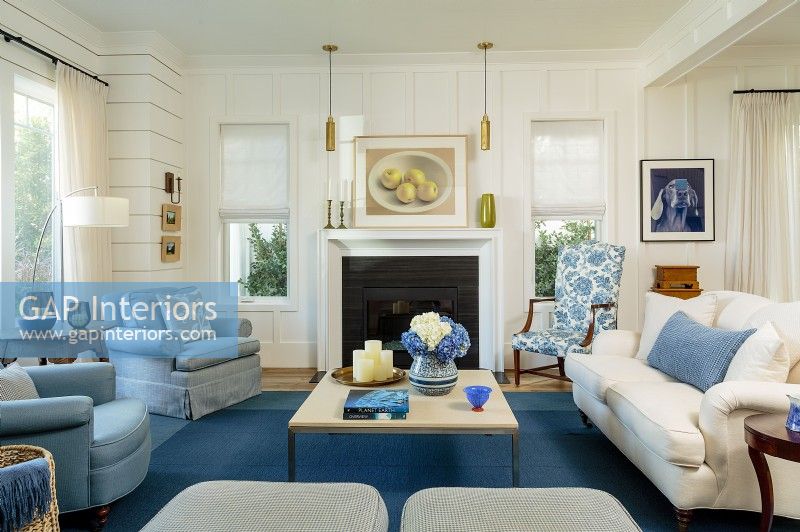 The living room welcomes with its crisp blue and white palette.  Shiplap and wood paneling instill a relax mood while modern light pendants inject a touch of modernity to the otherwise classic furnishings. A pair of ottoman adds structure and extra seating to the room.