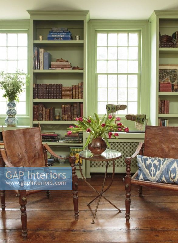 Refurbished chestnut floorboards highlight two perfectly preserved French campaign chairs acquired at a Paris flea market. The pieces are contrasted by a newer table and an exotic Ikat pillow. A pair of 1809 hand-beaded Native American rodeo gloves pays tribute to the past.