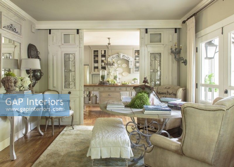 Once walled off from both the kitchen and living area, this sunny space plays dual roles as a dining room and a library. Antique French entry doors are suspended on tracks and wheelsâ€” barn door styleâ€”that are hidden by added-on crown molding. Doors are pull closed when needed but when left open guests can see the back kitchen walls from the front entry. 