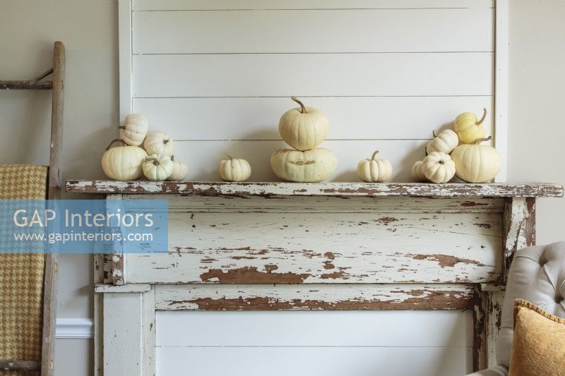 A vintage fireplace surround gets a subtle Fall makeover with grouping of tiny gourds in the same color family.