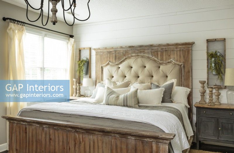  A shiplap wall and a variety of aged woods create a sense of history in the coupleâ€™s bedroom. The king-sized showstopper bed features a distressed headboard frame with tufted upholstery layered with a rustic whitewashed wooden mantel panel. 