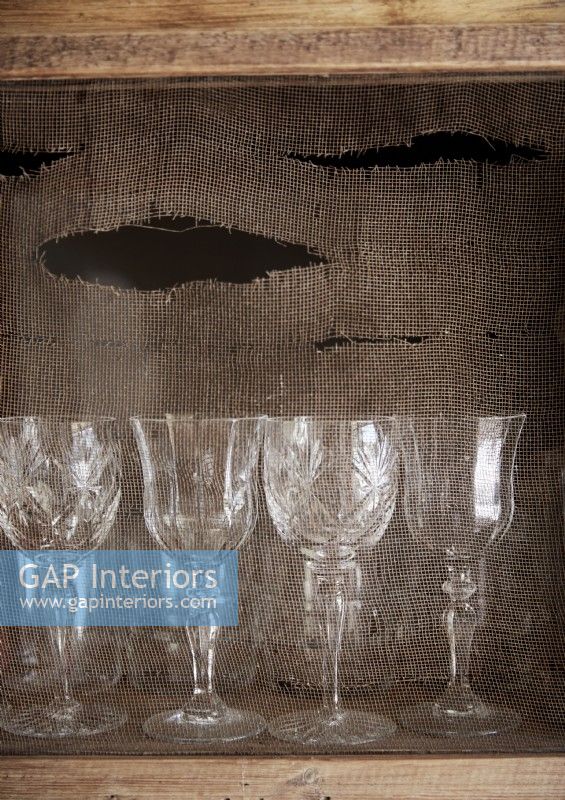 Detail of wine glasses on shelf backed with hessian sack