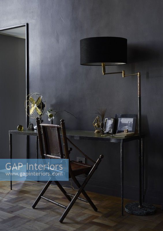 Black painted walls and desk with gold accessories 