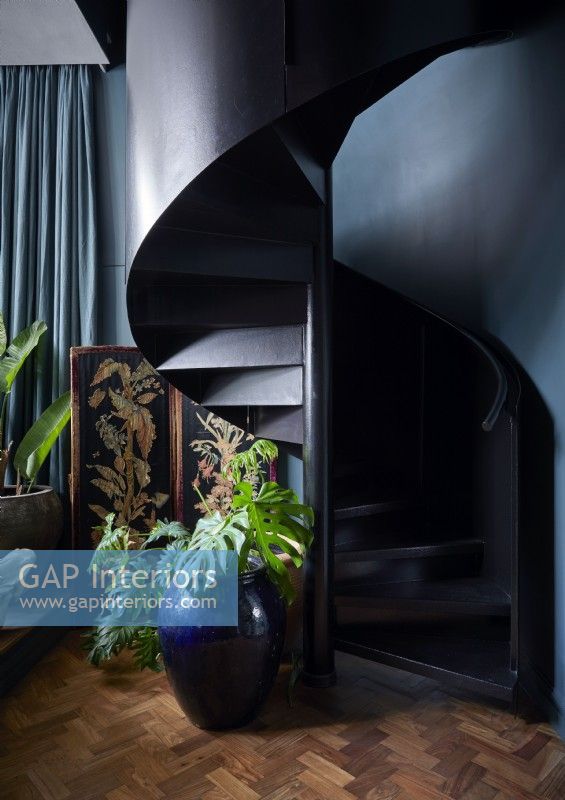 Black spiral staircase against blue painted wall