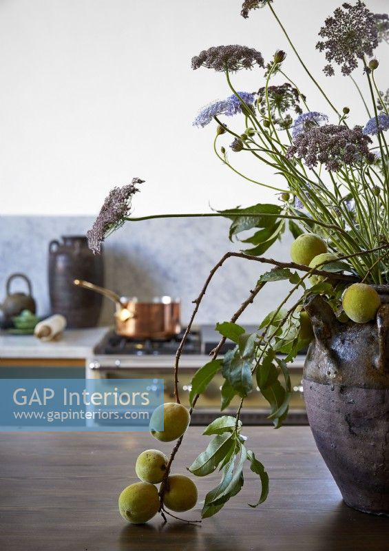 Flower and fruit display in large ceramic pot in country kitchen 