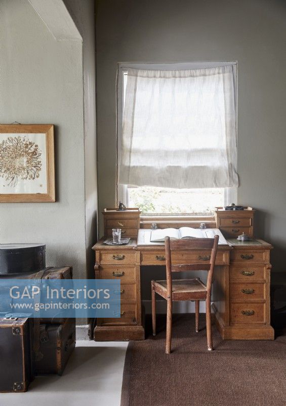 Wooden desk in country bedroom with vintage suitcases