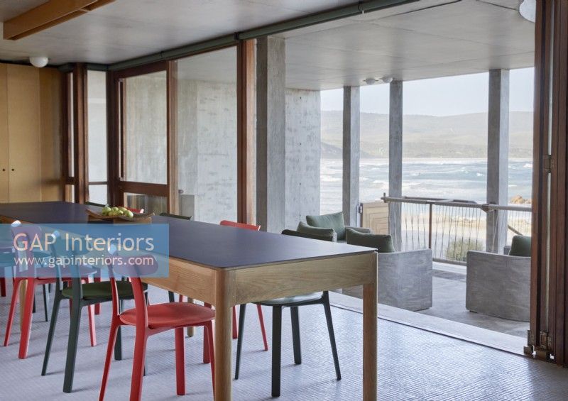 Colourful chairs around modern dining table with sea views
