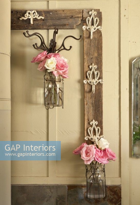 An old frame outfitted with hooks offers an unusual display spot for flower-filled jars.