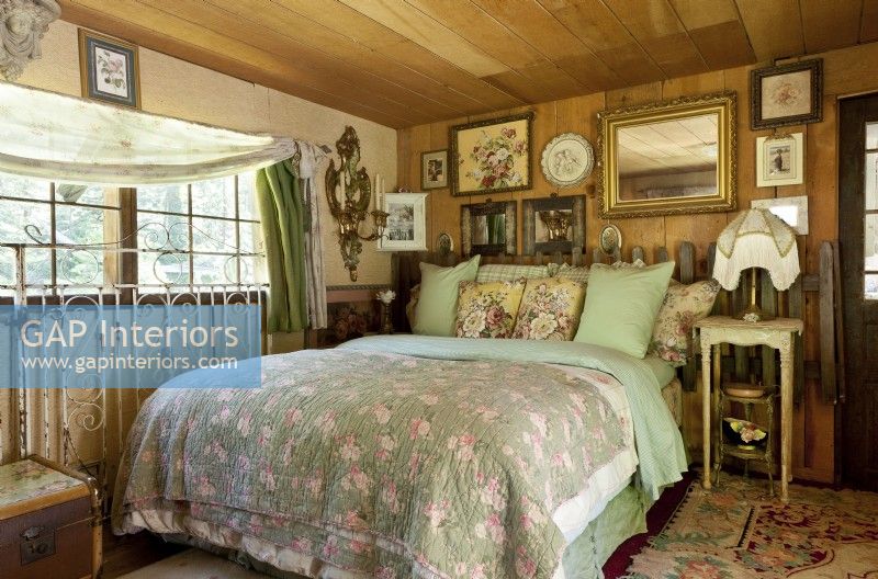Pre-loved, rugged furnishings and feminine floral fabrics meld primitive and pretty in the cozy guest bedroom. Layers of quilts and pillows give the inviting bed a nest-like feel.
