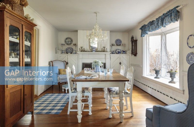 A Victorian fireplace mantle, a spacious table, a stately sideboard, and a blue and white theme sets the dining room French farmhouse comfort.