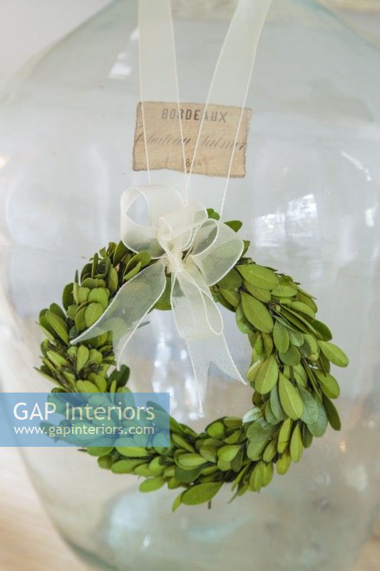 A tiny green wreath embellishes a vintage European demi-john bottle.