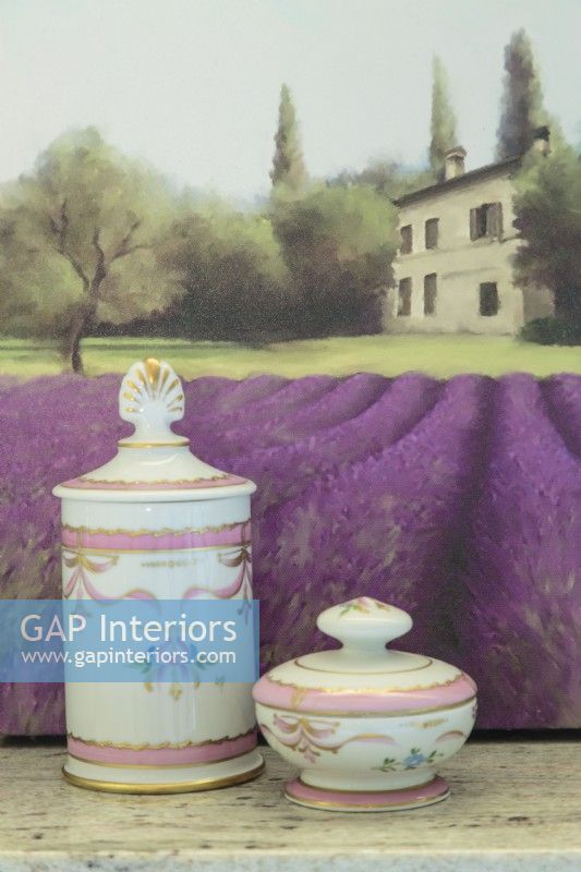A small painting of a chateau and lavender fields backs a delicate Limoges bath set. 