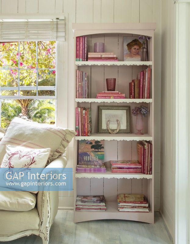 The rusticity of the  bookcase is soften with a coat of pale pink and a dainty scalloped trim.