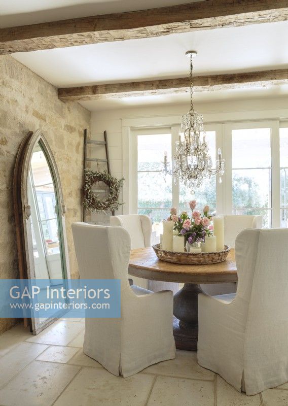 Leah Anderson decorates with fewer pieces, each with show-stopping style, like the pedestal table and a salvaged, gothic-arch window made into a stately mirror frame.
