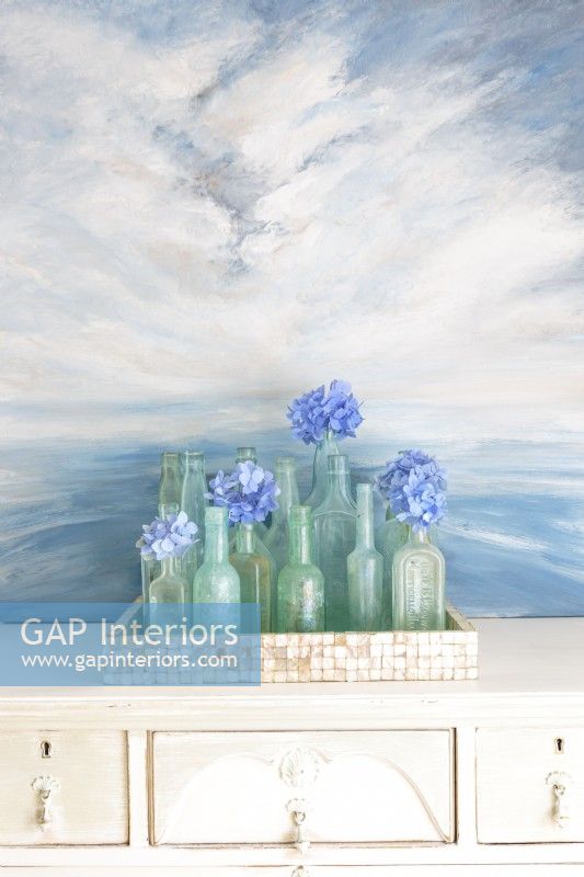 A painting by Erin forms the perfect backdrop for collection of vintage aqua bottles. 