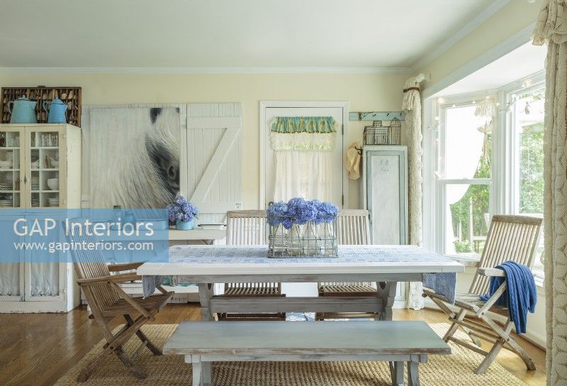 Weathered teak  garden chairs and a bench provide seating for a trestle table in the kitchen area.