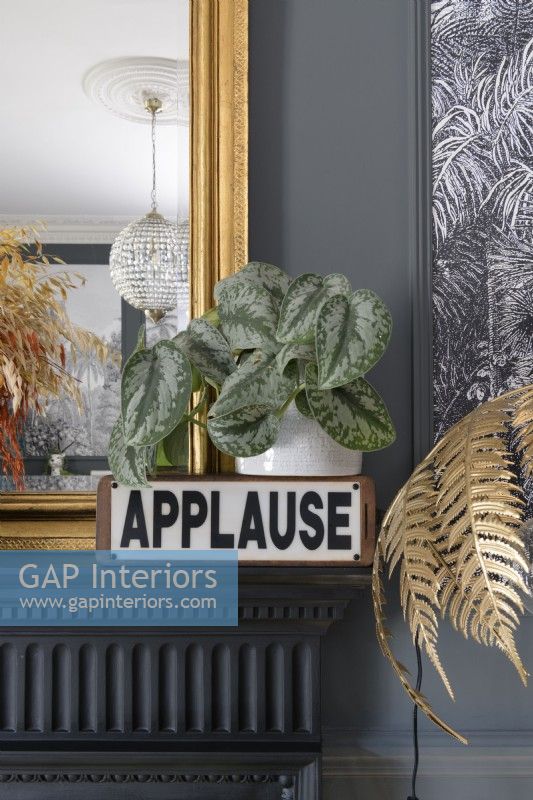 Detail of a vintage applause lamp on a mantlepiece with a gold framed mirror 
