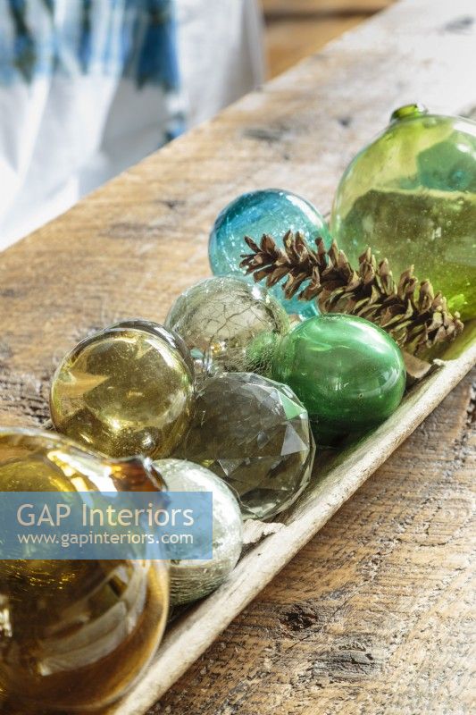 Glass fishing floats add bright spots of color to the rustic coffee table.