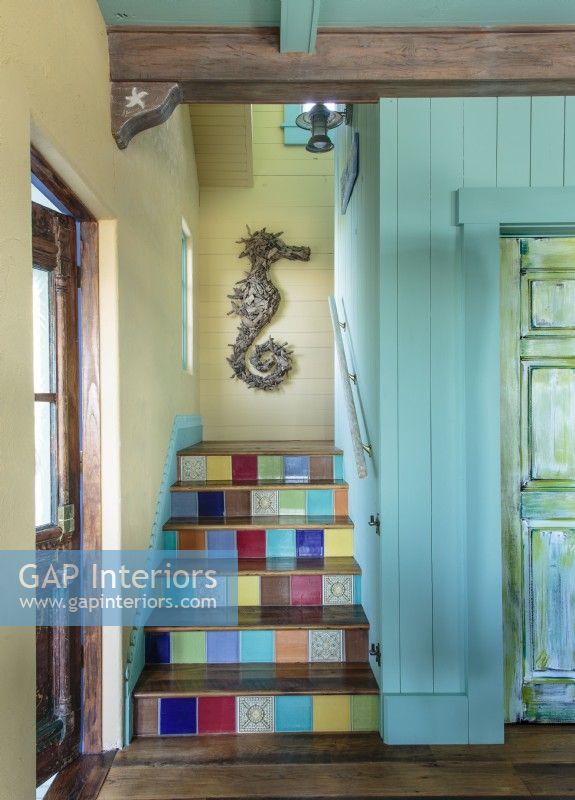 The staircase leading to the upstairs bedrooms was outfitted with a rainbow of tiles, custom woodwork and coastal art. 
