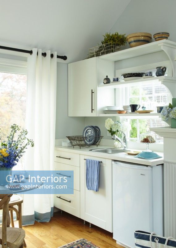 White cabinets and counters complement the classic cottage style and help make the little home feel more spacious.