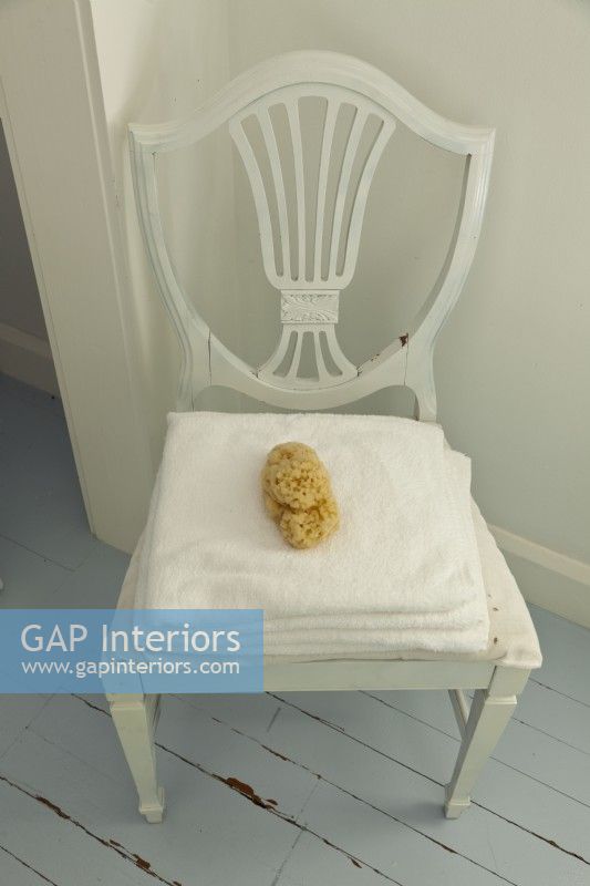 A vintage chair makes a stylish spot for towels and a natural sponge