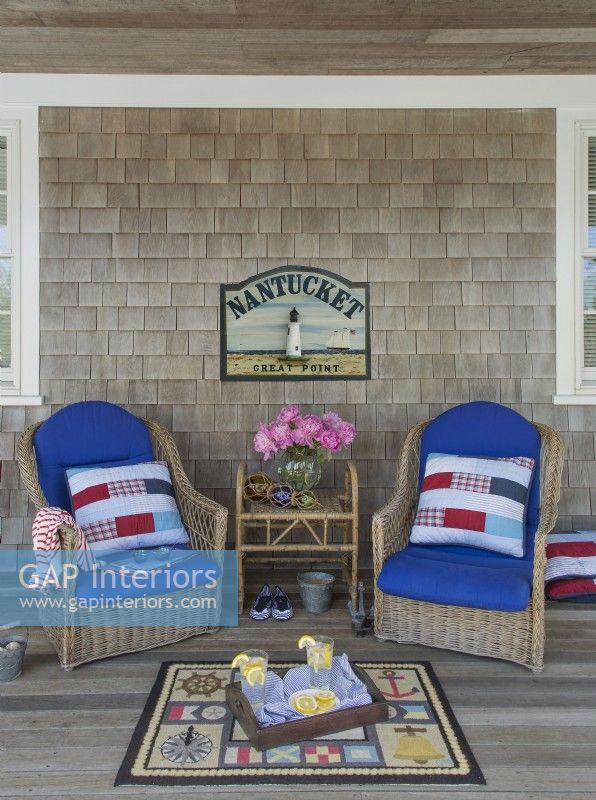 Wicker chairs on the porch welcome visitors. Glass fishing floats add nautical flair.