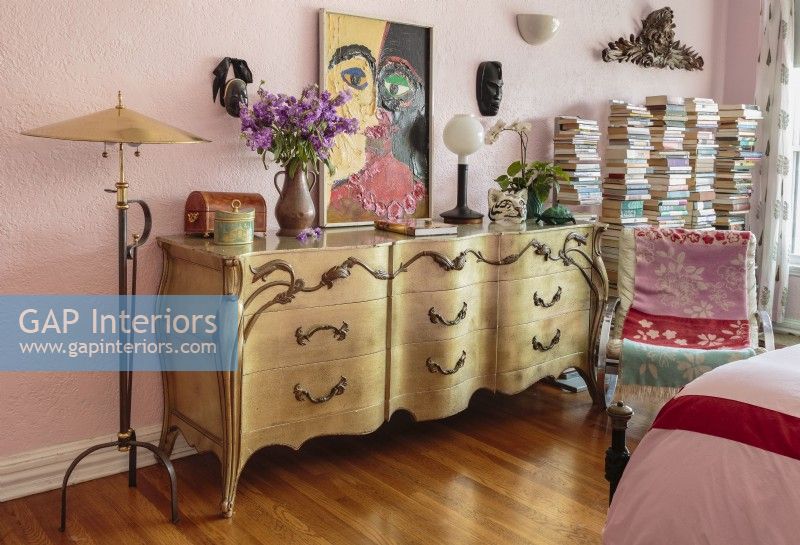 Carved African mask and a quirky painted portrait hang over a continental bombÃ© dresser.
