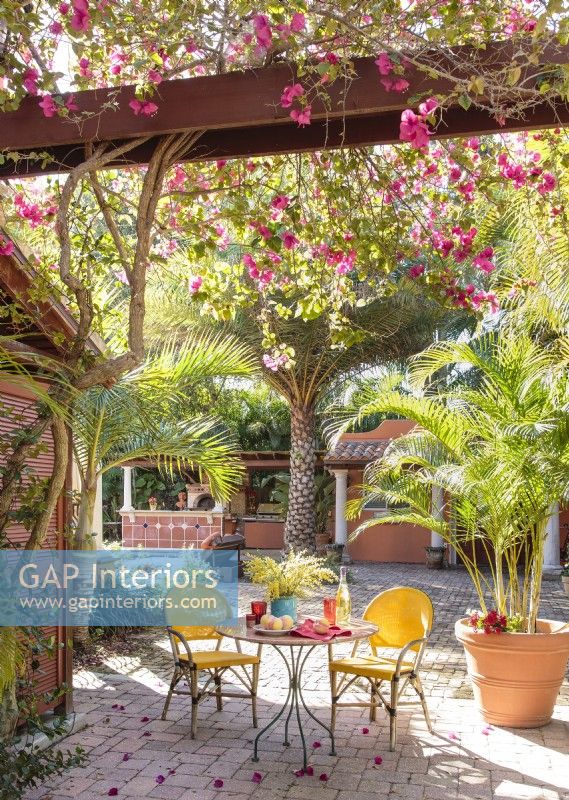 A bistro table tucked under bougainvillea vines and palms evoke an open-air Tuscan courtyard 