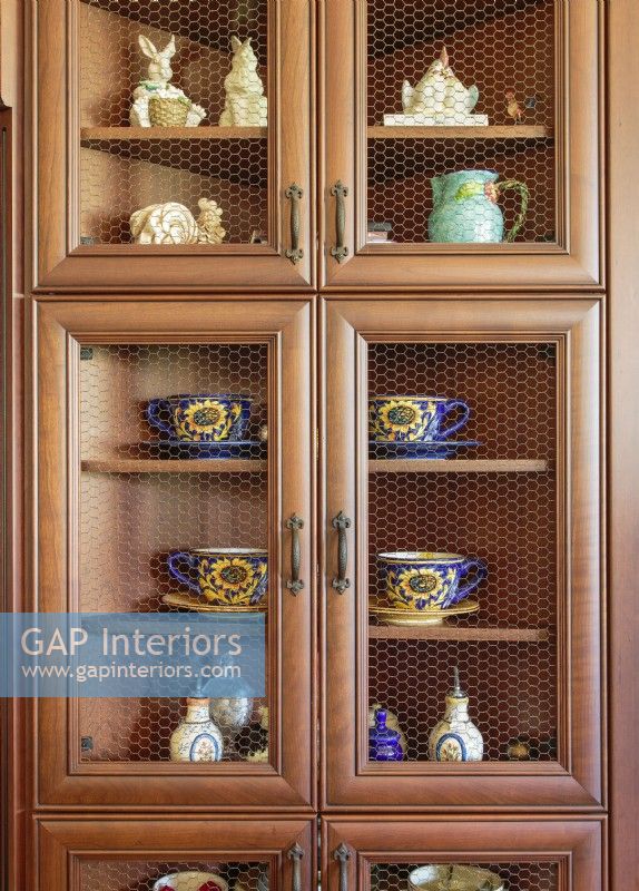 Treasures displayed in a wire-front cabinet include vintage sunflower cups and saucers, mustard jars,