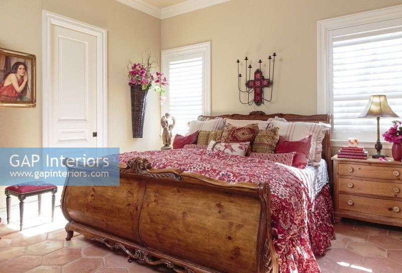 The color of the bed linens are reflected around the room in coppery hexagon Saltillo floor tiles, paintings, and other decorative accents