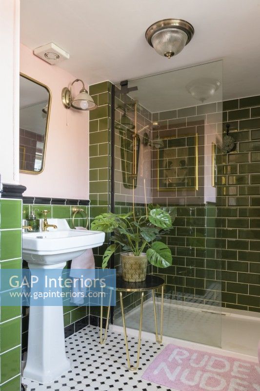White and sink and shower cubicle in a green tiled and pale pink bathroom 
