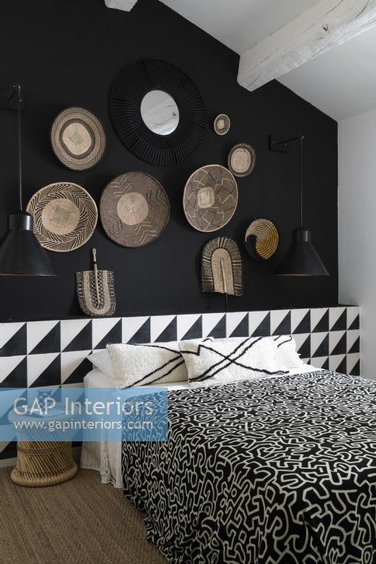 Display of baskets on black wall of monochrome bedroom