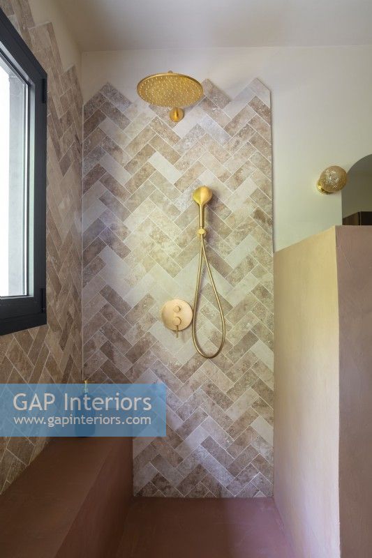 Brown stone tiling and gold taps in shower cubicle