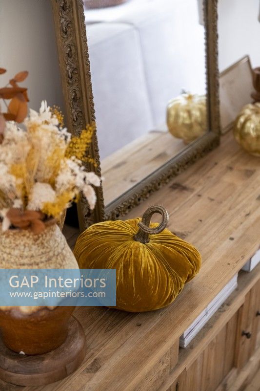 Golden velvet pumpkin decoration on wooden sideboard