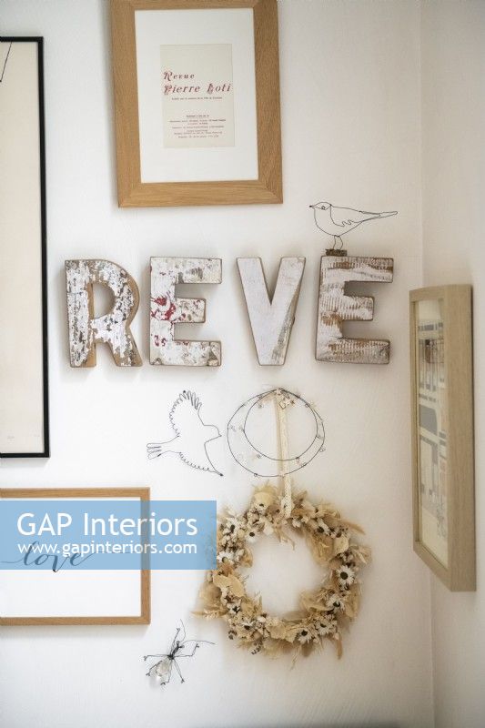 Detail of distressed wooden lettering and framed art on wall