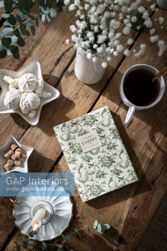 Floral notebook and Christmas treats on wooden coffee table - detail