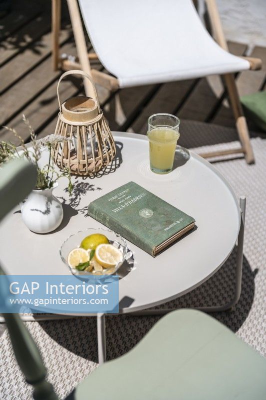 Drink, book and lantern on small garden table in outdoor living area