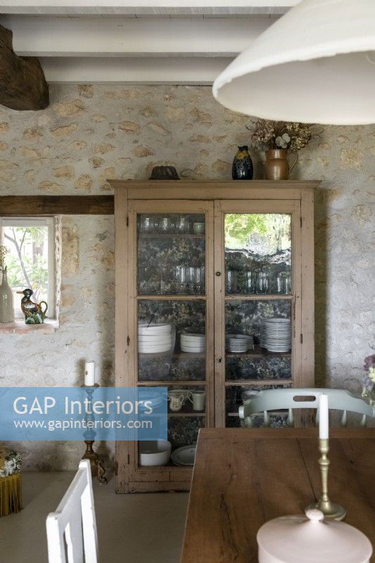 Wooden dresser against exposed stone wall in country dining room