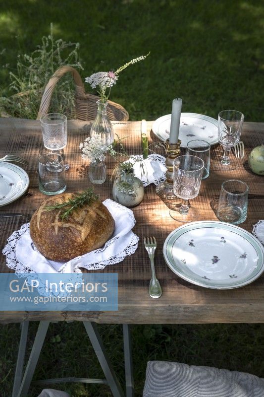Detail of rustic outdoor dining table laid for lunch