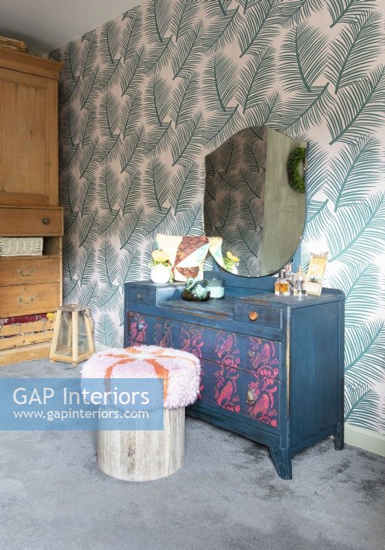 Painted dressing table against wallpapered wall in eclectic bedroom