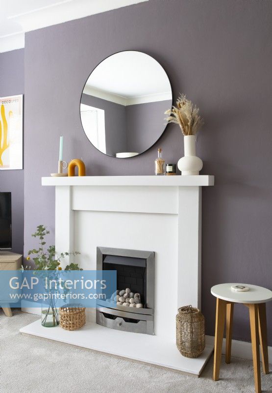 White fireplace surround against purple painted wall 