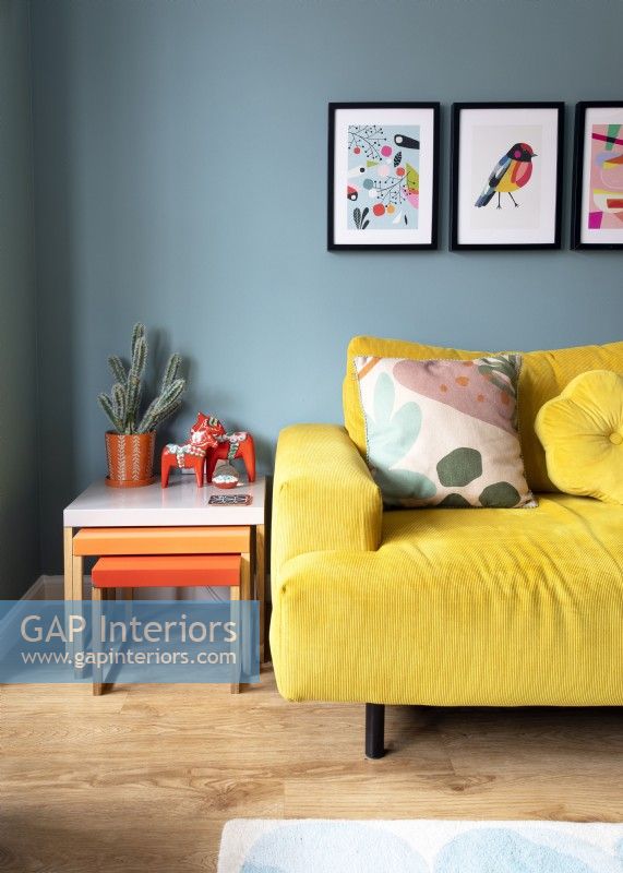 Yellow sofa and orange nest of tables in colourful living room