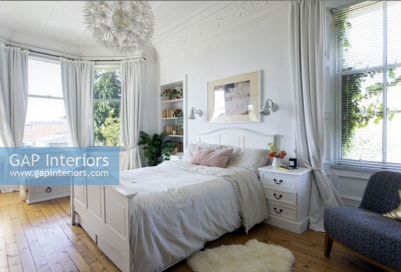 White feminine bedroom with wooden flooring